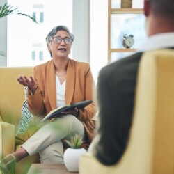 Talking, psychologist and man for therapy, advice or discussion of mental health. Meeting, consultation and a female therapist with a patient for counseling support, conversation or help in an office